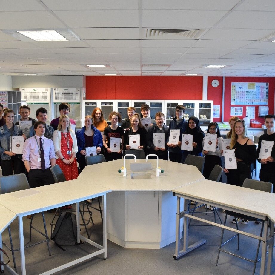 Chemistry students in lab with Olympiad certificates